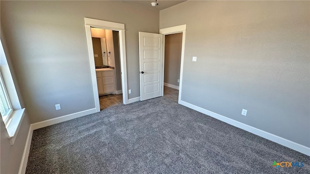 unfurnished bedroom featuring dark carpet and ensuite bathroom