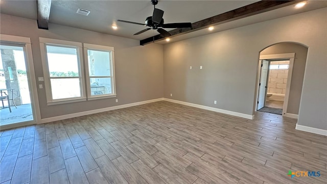 unfurnished room featuring light wood-type flooring, a wealth of natural light, beamed ceiling, and ceiling fan