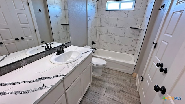 full bathroom featuring tiled shower / bath, toilet, and vanity