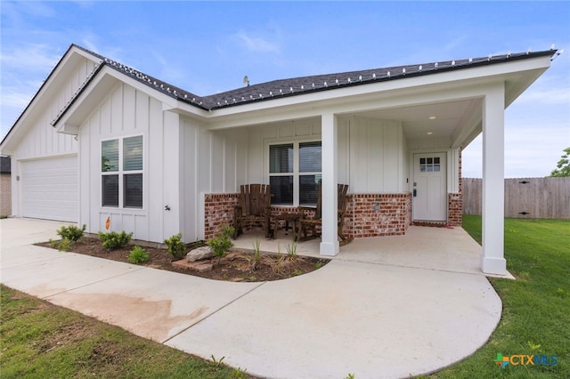 view of front of property featuring fence, brick siding, board and batten siding, a front yard, and driveway