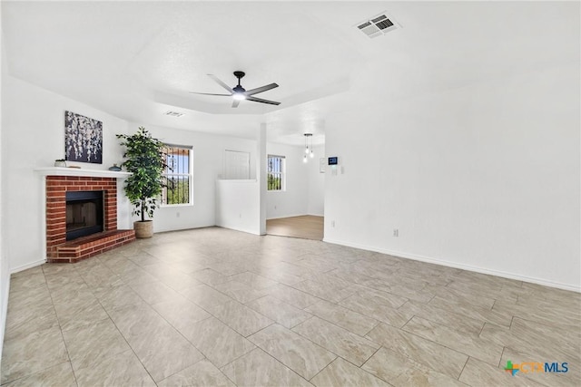 unfurnished living room featuring a ceiling fan, visible vents, baseboards, and a fireplace