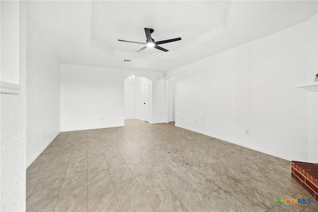 unfurnished room featuring visible vents, arched walkways, a ceiling fan, and a tray ceiling