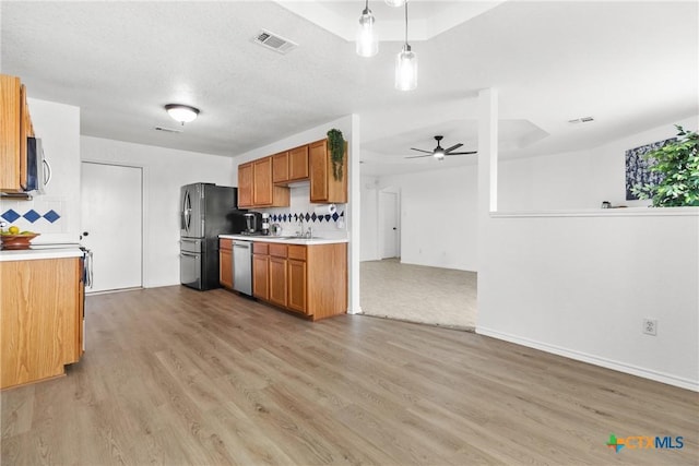 kitchen featuring light wood finished floors, stainless steel appliances, ceiling fan, visible vents, and light countertops