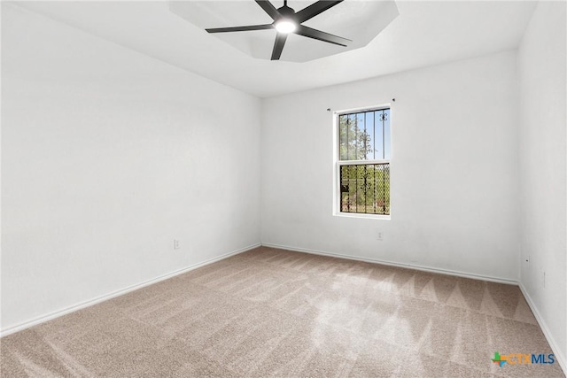 carpeted spare room featuring baseboards and ceiling fan