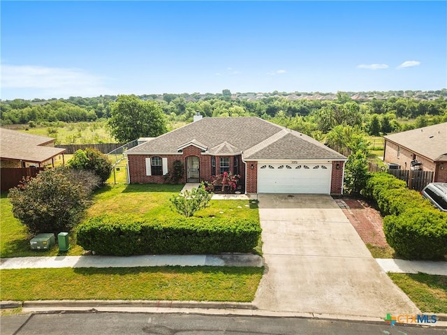 ranch-style home with a front lawn, a garage, driveway, brick siding, and fence