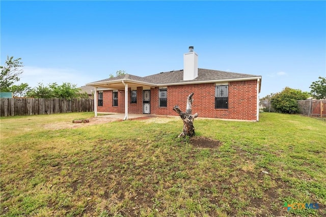 back of property with a patio, a yard, a fenced backyard, and brick siding