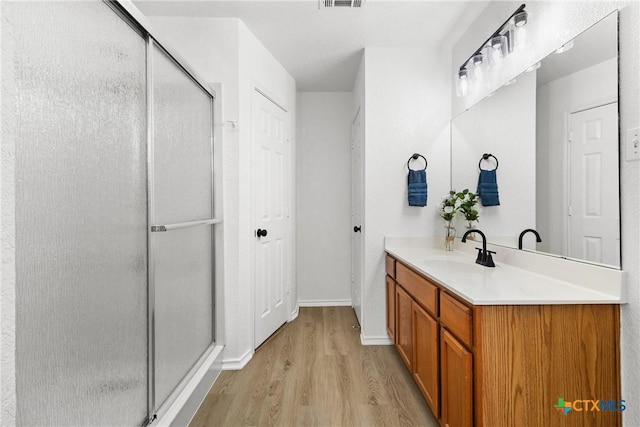 full bathroom with visible vents, wood finished floors, a stall shower, and vanity