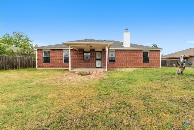 rear view of property with brick siding, fence, a chimney, and a patio area