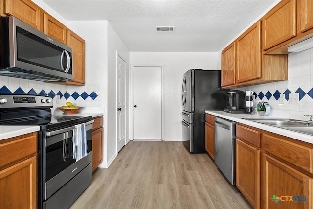 kitchen with tasteful backsplash, visible vents, appliances with stainless steel finishes, and light wood finished floors