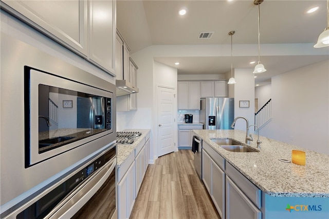 10259 Juniper Oaks, Boerne, TX 78006 - kitchen featuring appliances with stainless steel finishes, light wood-style floors, a center island with sink, pendant lighting, and range hood