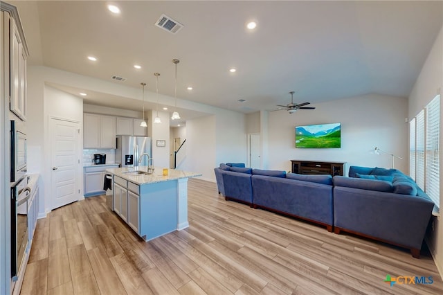 10259 Juniper Oaks, Boerne, TX 78006 - kitchen featuring appliances with stainless steel finishes, open floor plan, light wood-style floors, a ceiling fan, and a center island with sink