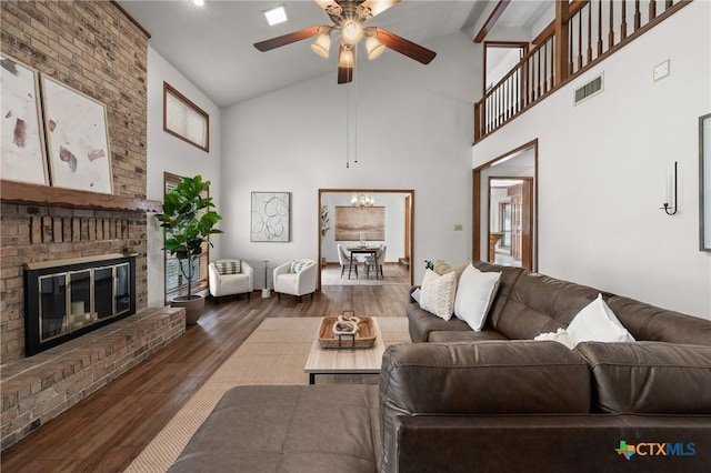 living room featuring visible vents, wood finished floors, a fireplace, high vaulted ceiling, and ceiling fan with notable chandelier