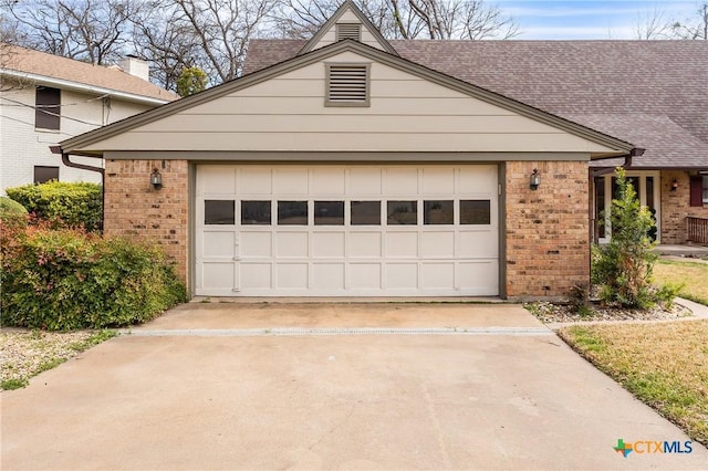 view of front of home with driveway, roof with shingles, an attached garage, and brick siding