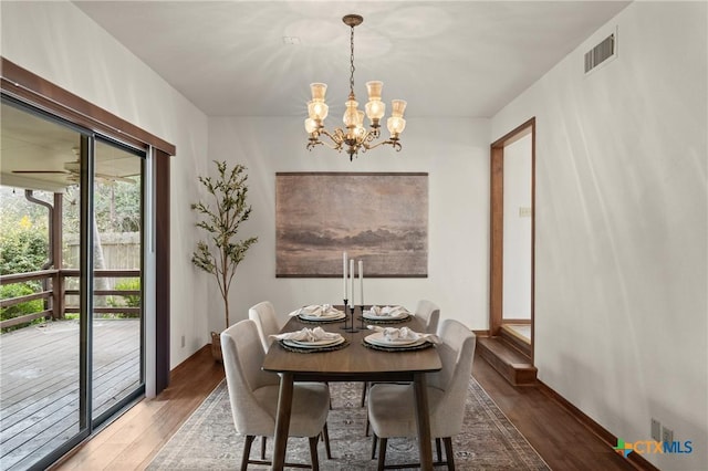 dining room featuring baseboards, visible vents, wood finished floors, and ceiling fan with notable chandelier