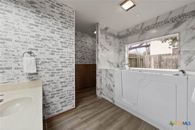 full bathroom featuring vanity, wood finished floors, and a washtub