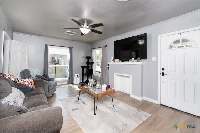 living room featuring light wood-type flooring, ceiling fan, and crown molding