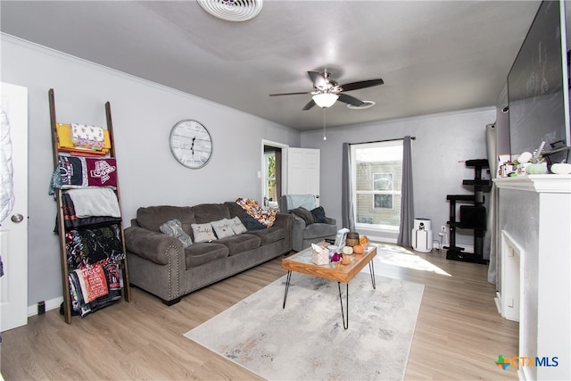 living room featuring ornamental molding, light wood-type flooring, and ceiling fan