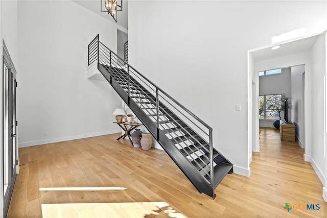 stairs featuring a high ceiling, hardwood / wood-style flooring, and a notable chandelier