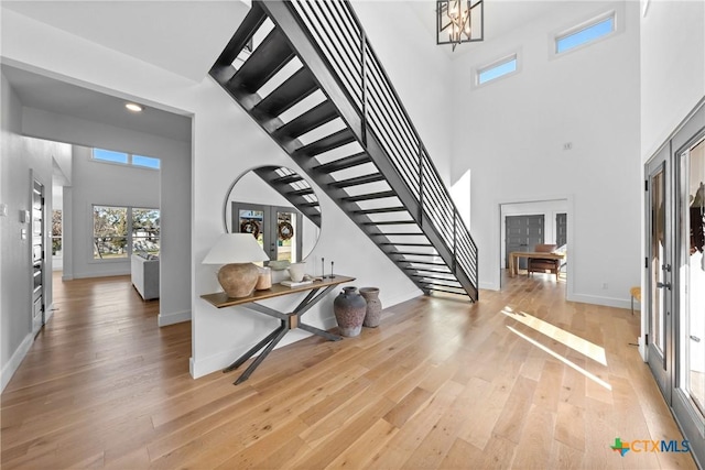 entryway featuring light wood-type flooring, french doors, and a towering ceiling