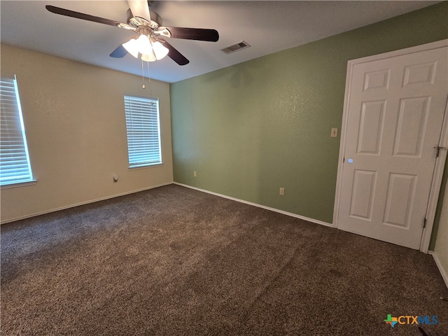 unfurnished room featuring ceiling fan and dark carpet