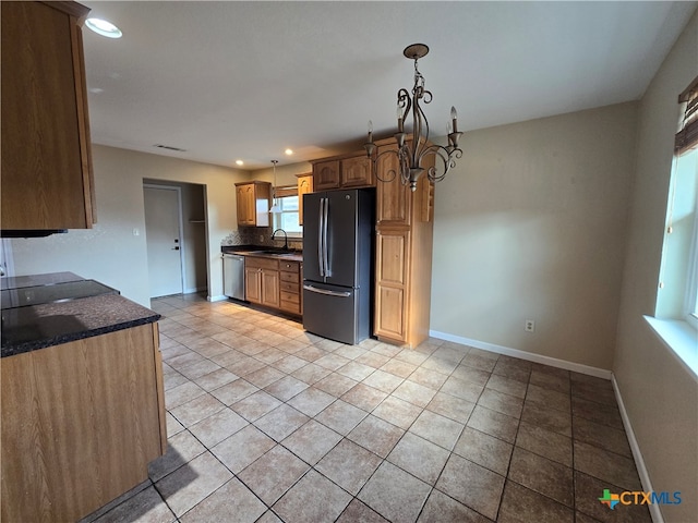 kitchen featuring black fridge, light tile patterned flooring, sink, stainless steel dishwasher, and a chandelier