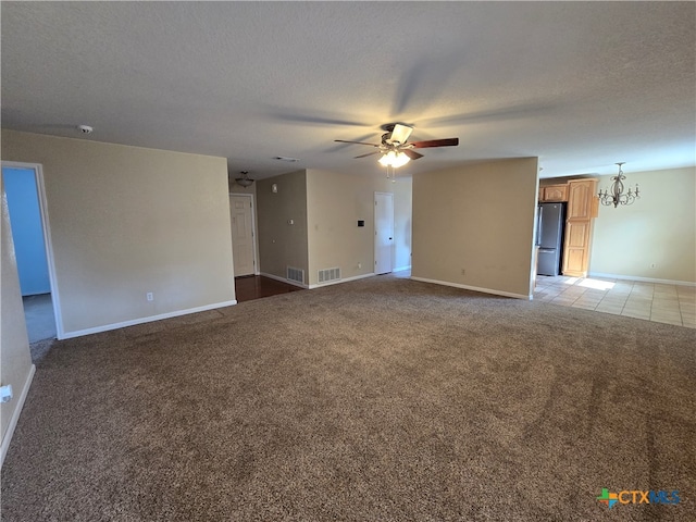 unfurnished room with ceiling fan with notable chandelier, light colored carpet, and a textured ceiling