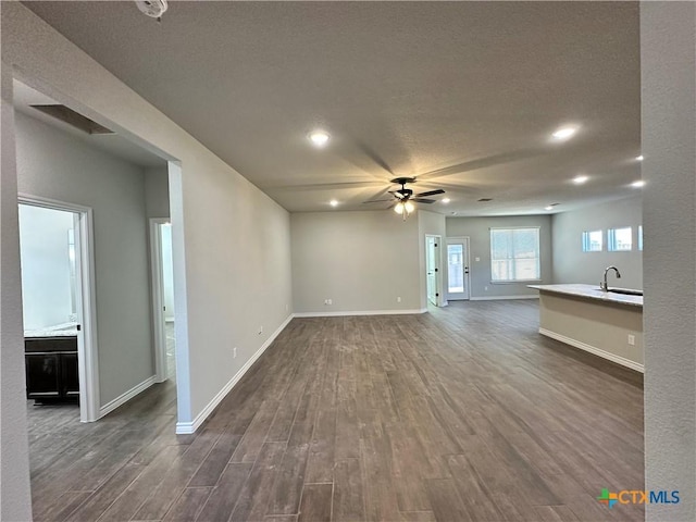 unfurnished living room featuring ceiling fan, dark hardwood / wood-style flooring, and sink