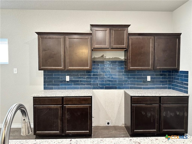 kitchen featuring decorative backsplash, wood-type flooring, dark brown cabinetry, and light stone counters