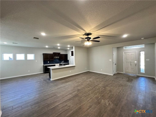 unfurnished living room with dark hardwood / wood-style flooring, ceiling fan, sink, and a textured ceiling