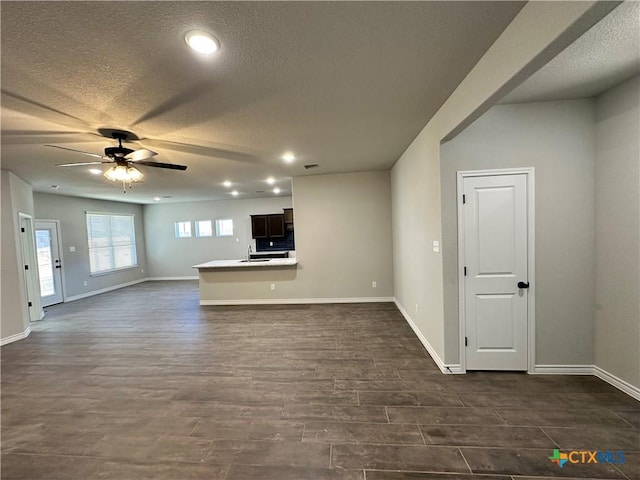 unfurnished living room featuring ceiling fan, dark hardwood / wood-style floors, and a textured ceiling