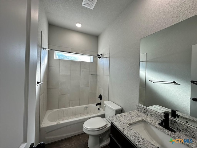 full bathroom with vanity, tile patterned floors, tiled shower / bath, toilet, and a textured ceiling