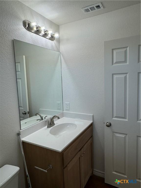 bathroom featuring vanity, a textured ceiling, and toilet