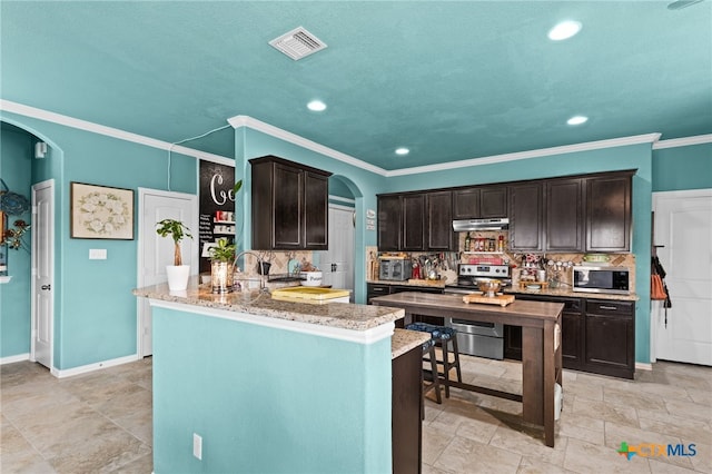 3700 Joyce Ln, Killeen, TX 76549 - kitchen with appliances with stainless steel finishes, arched walkways, dark brown cabinets, backsplash, and recessed lighting