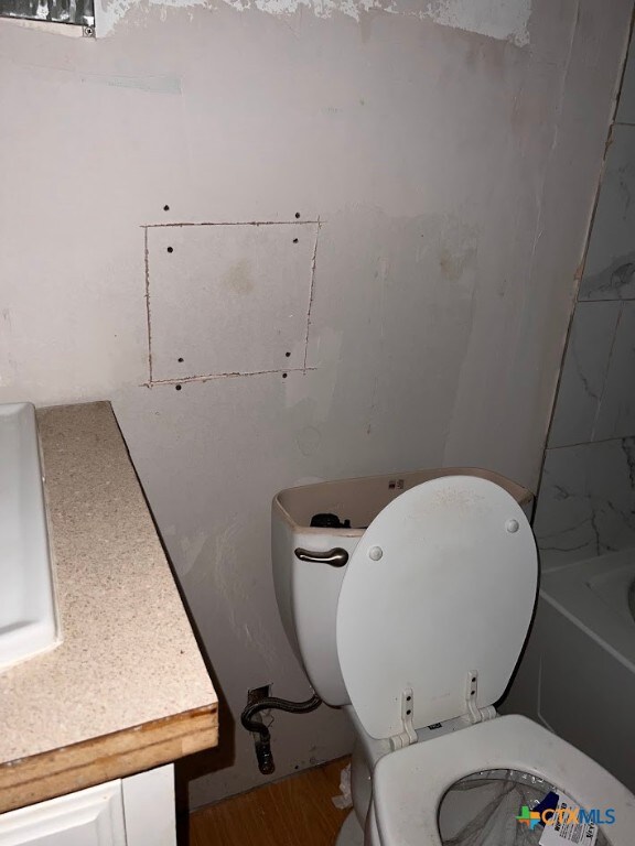 bathroom featuring toilet, vanity, hardwood / wood-style floors, and a bathtub