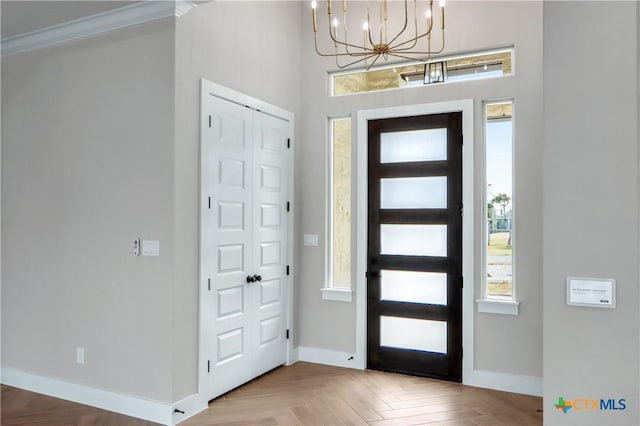 entrance foyer with baseboards, a notable chandelier, and crown molding