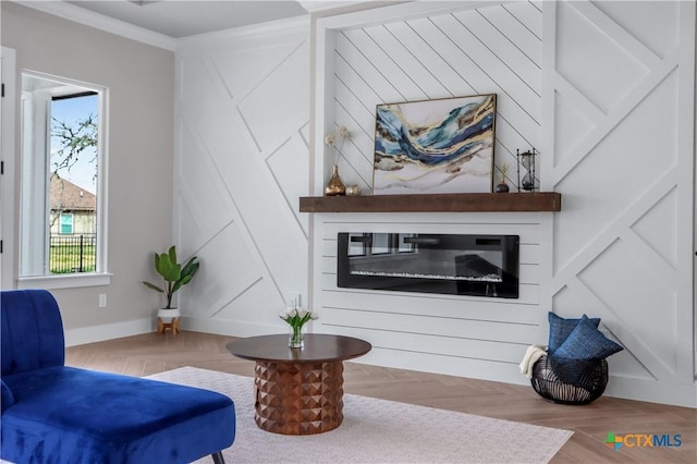 sitting room featuring ornamental molding, plenty of natural light, a glass covered fireplace, and wood finished floors