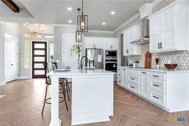 kitchen featuring hanging light fixtures, light countertops, white cabinets, an island with sink, and stainless steel appliances