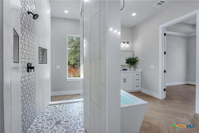 bathroom featuring vanity, baseboards, visible vents, a freestanding tub, and a walk in shower