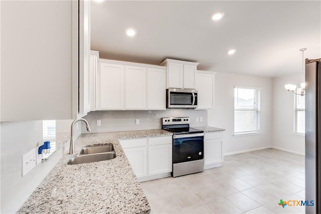 kitchen featuring stainless steel appliances, sink, white cabinets, a chandelier, and hanging light fixtures