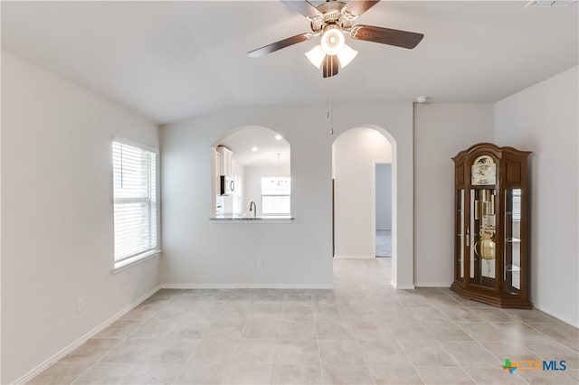 tiled empty room with vaulted ceiling, ceiling fan, and sink