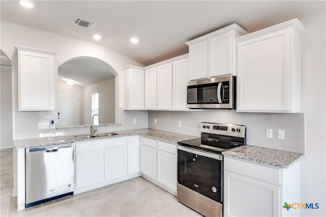 9019 Stonehollow Rd, Temple, TX 76502 - kitchen featuring appliances with stainless steel finishes, a sink, lofted ceiling, arched walkways, and white cabinetry