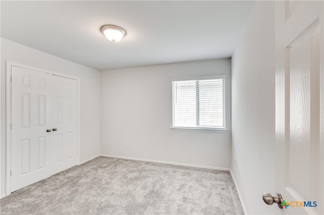 unfurnished bedroom featuring a closet and light colored carpet