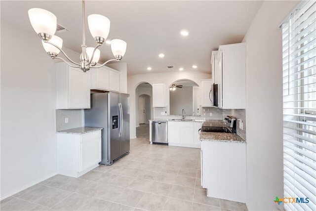 9019 Stonehollow Rd, Temple, TX 76502 - kitchen featuring stainless steel appliances, arched walkways, decorative backsplash, light tile patterned floors, and light stone countertops