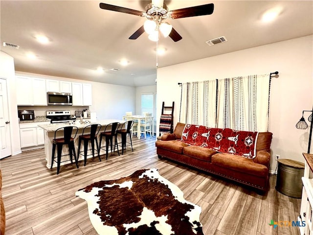 living room featuring ceiling fan and light hardwood / wood-style floors