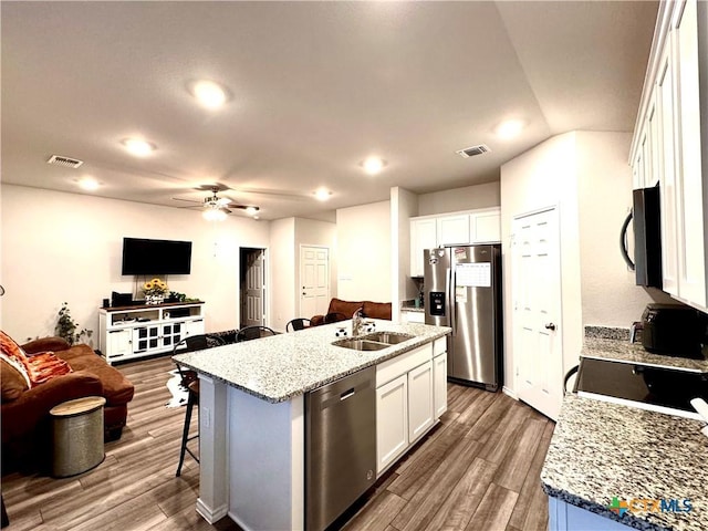 kitchen featuring a kitchen island with sink, white cabinets, stainless steel appliances, and dark hardwood / wood-style floors