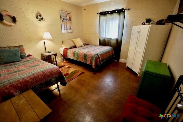 bedroom featuring concrete block wall and concrete flooring