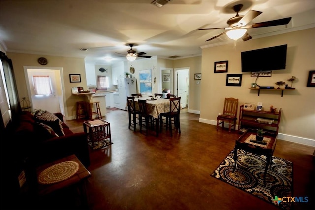 dining room featuring baseboards, concrete floors, a ceiling fan, and crown molding