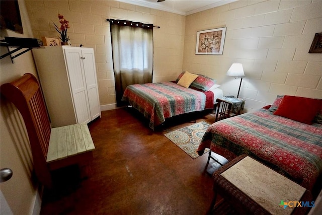 bedroom featuring crown molding, finished concrete flooring, and concrete block wall