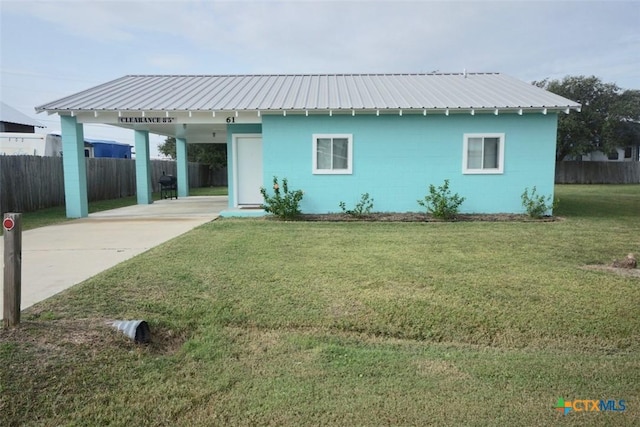 ranch-style house featuring metal roof, a carport, concrete block siding, and a front lawn