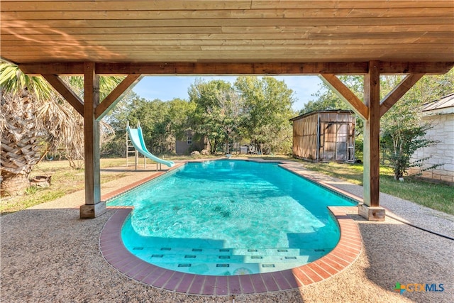 view of pool featuring a patio, a storage unit, and a water slide